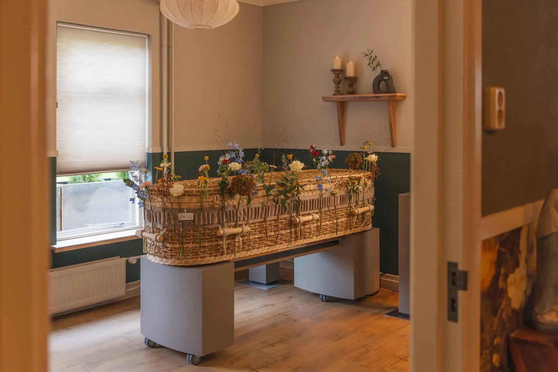 Echte afscheidskamer van het Afscheidshuus met een met veldbloemen versierde rieten kist