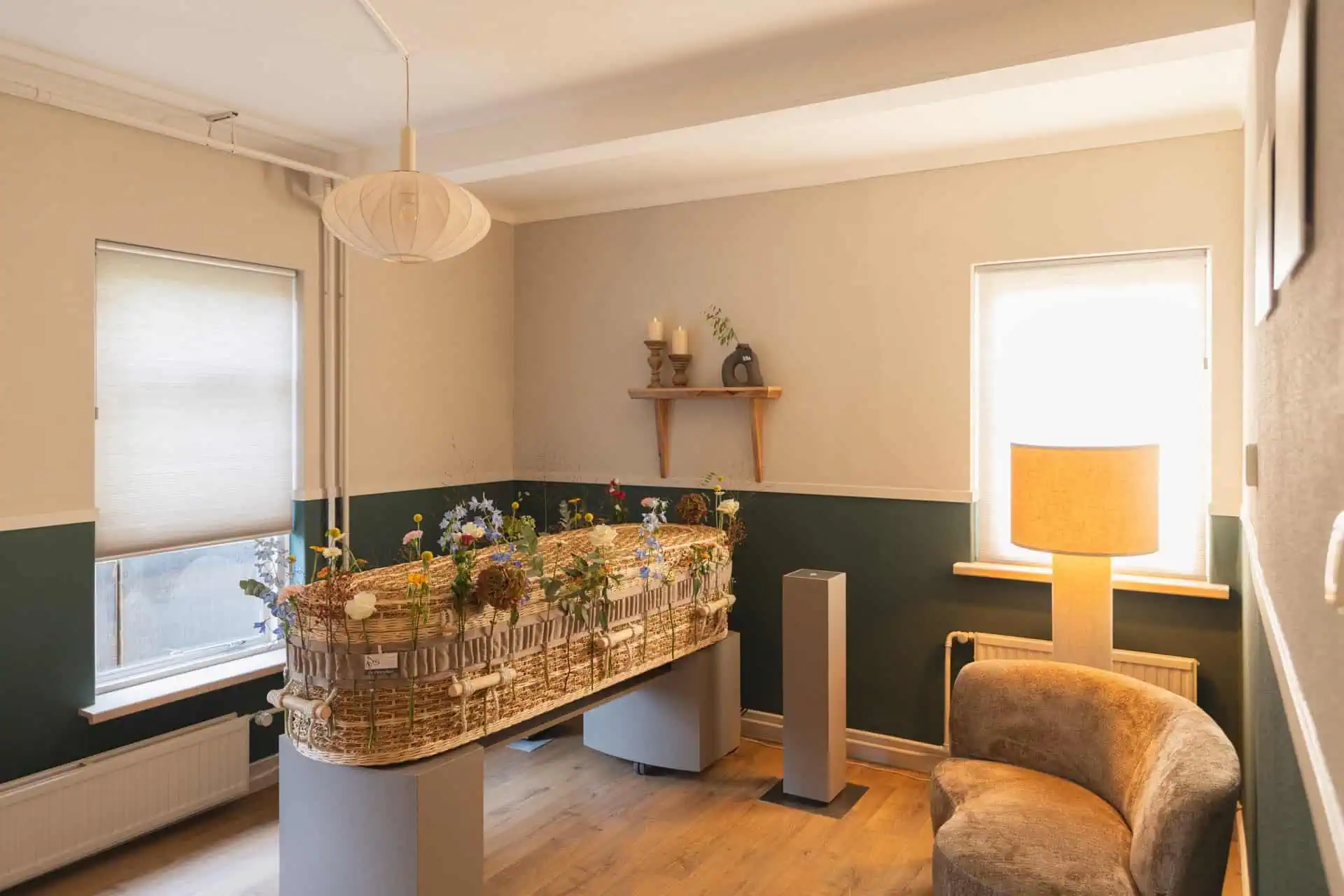Lichte afscheidskamer met rieten kist en veldbloemen